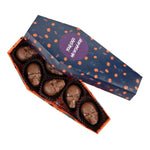Chocolade doodskist met logo: geopende donkerblauwe doos met schedelpralines van melkchocolade