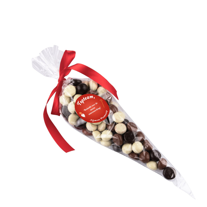 Transparante puntzak gevuld met snoep, met rood lintje en ronde sticker met logo: Gemengde Chocolade Kruidnoten