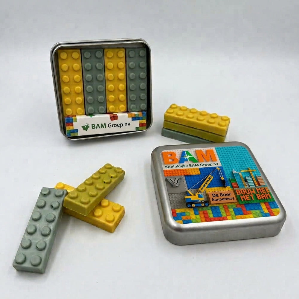 Geopend blik met vier chocolade bouwstenen in lego-stijl naast het bedrukte deksel met eigen ontwerp