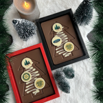 Twee tabletten van melkchocolade met kerstboom en drie chocodrops met voorbeeldlogo, in een rood en een zwart doosje