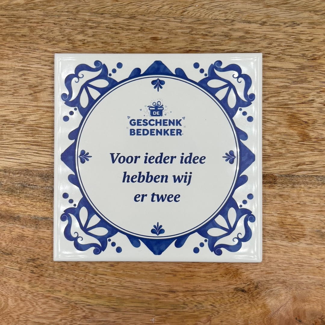 Bedrukt tegeltje met Delfts blauw kader en de tekst Voor ieder idee hebben wij er twee op een houten ondergrond