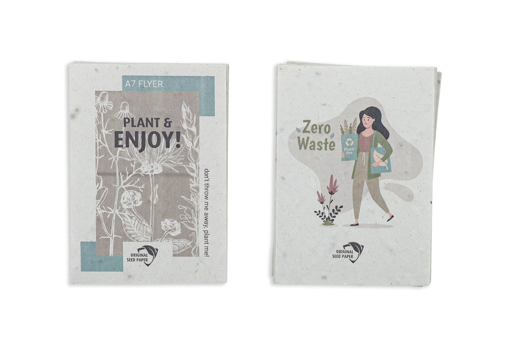 Bedrukte A7-flyer van zaadpapier naast takjes met witte bloemetjes